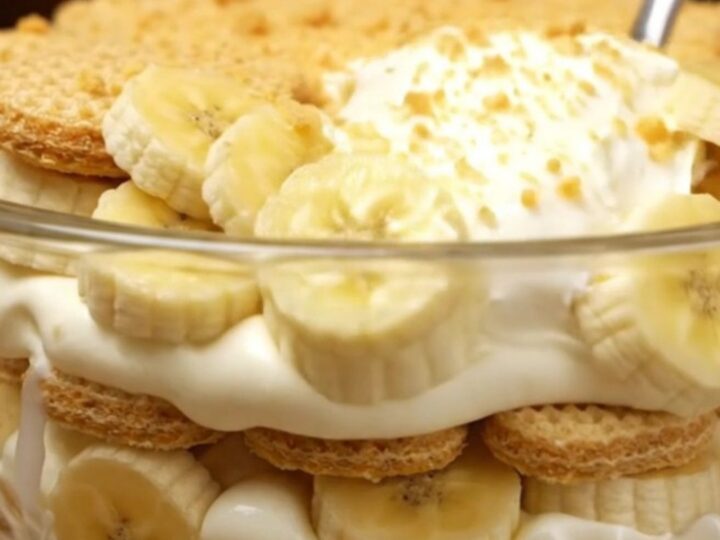 A large glass trifle bowl filled with layers of creamy vanilla pudding, fresh banana slices, and golden vanilla wafers.