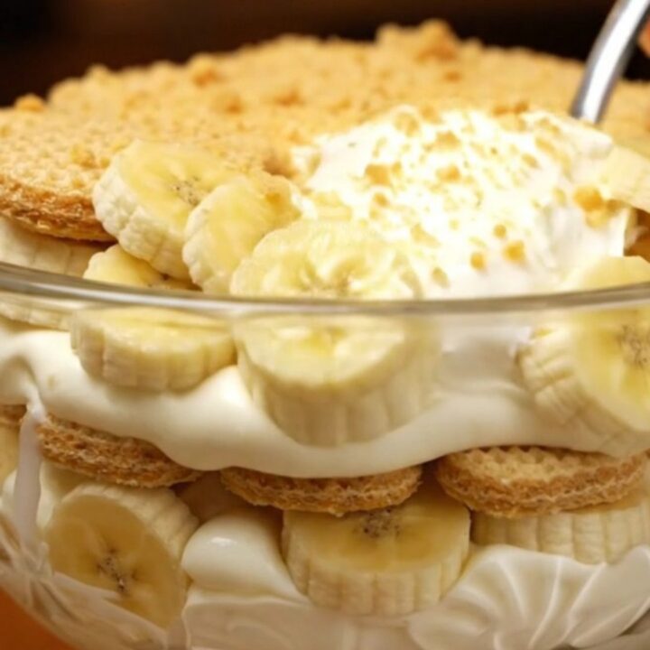 A large glass trifle bowl filled with layers of creamy vanilla pudding, fresh banana slices, and golden vanilla wafers.