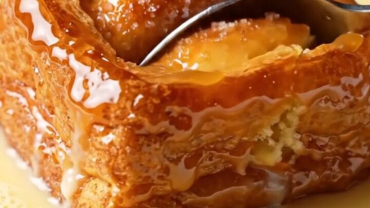A close-up of a caramelized golden-brown brioche slice with a crispy sugar crust and a soft, custard-soaked interior.