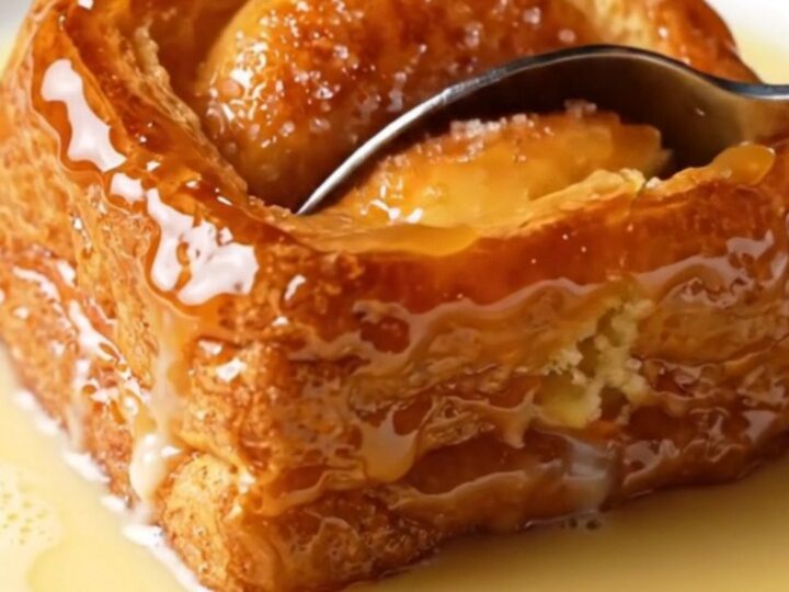 A close-up of a caramelized golden-brown brioche slice with a crispy sugar crust and a soft, custard-soaked interior.