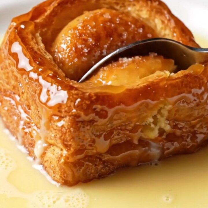 A close-up of a caramelized golden-brown brioche slice with a crispy sugar crust and a soft, custard-soaked interior.