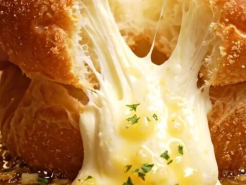 A close-up shot of a Korean garlic cream cheese brioche bun being pulled apart to reveal the creamy filling.