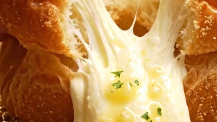 A close-up shot of a Korean garlic cream cheese brioche bun being pulled apart to reveal the creamy filling.