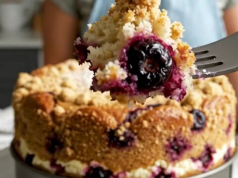 A slice of golden lemon blueberry ricotta cake topped with large, buttery cinnamon streusel boulders.