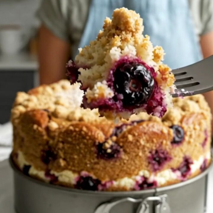 A slice of golden lemon blueberry ricotta cake topped with large, buttery cinnamon streusel boulders.