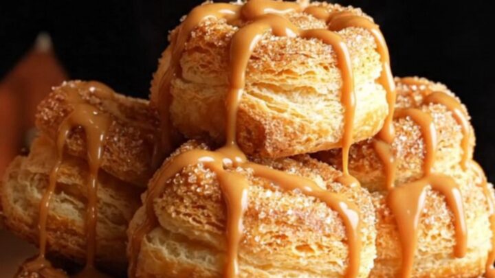 Close-up of golden, crispy churro cheesecake pinwheels with a visible creamy vanilla center.
