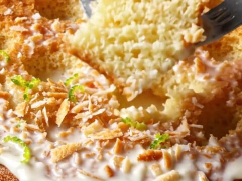 A slice of tropical Coconut Tres Leches cake topped with toasted coconut and lime zest on a plate.