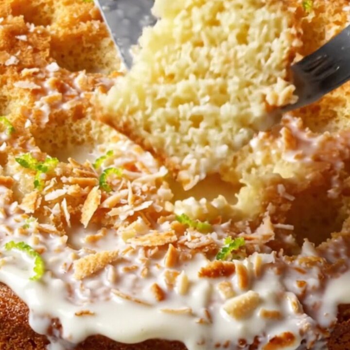 A slice of tropical Coconut Tres Leches cake topped with toasted coconut and lime zest on a plate.