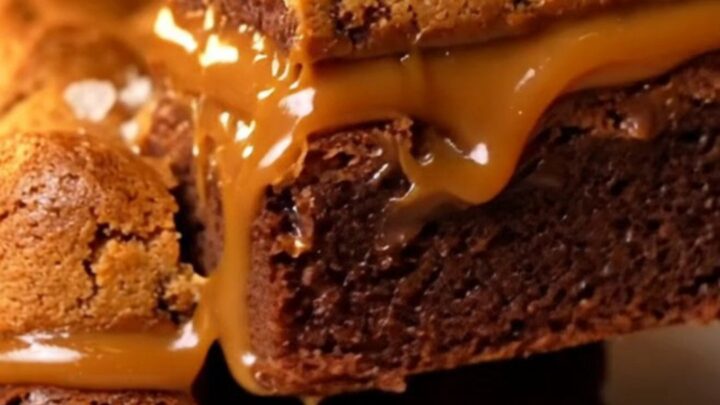 A stack of three-layer brookie bars showing a fudgy brownie base, a thick layer of salted caramel
