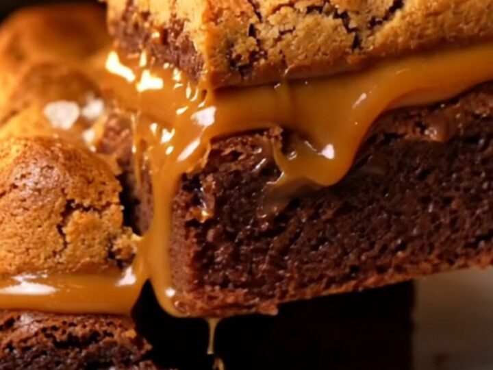 A stack of three-layer brookie bars showing a fudgy brownie base, a thick layer of salted caramel