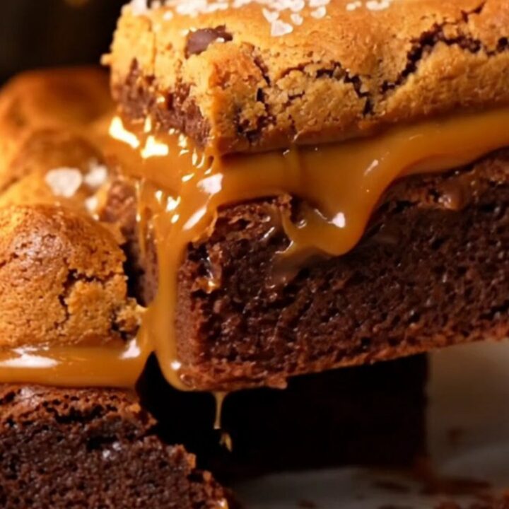 A stack of three-layer brookie bars showing a fudgy brownie base, a thick layer of salted caramel