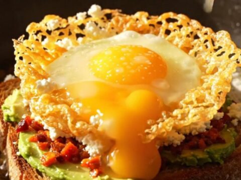 A close-up of a crispy golden feta ring surrounding a runny egg on a slice of sourdough bread.
