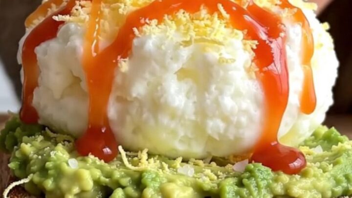A close-up of two pieces of sourdough toast topped with creamy avocado and a light layer of grated hard-boiled egg.