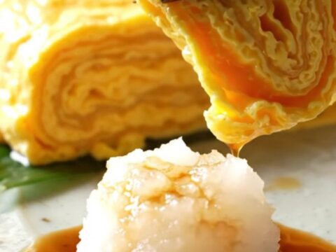 A close-up of a golden, multi-layered Japanese tamagoyaki omelette sliced into perfect rectangular pieces.