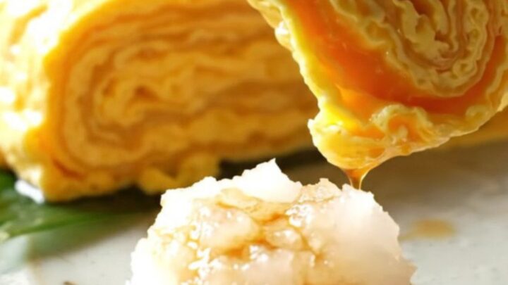 A close-up of a golden, multi-layered Japanese tamagoyaki omelette sliced into perfect rectangular pieces.