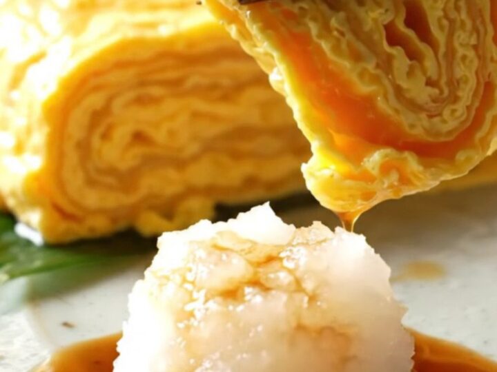 A close-up of a golden, multi-layered Japanese tamagoyaki omelette sliced into perfect rectangular pieces.