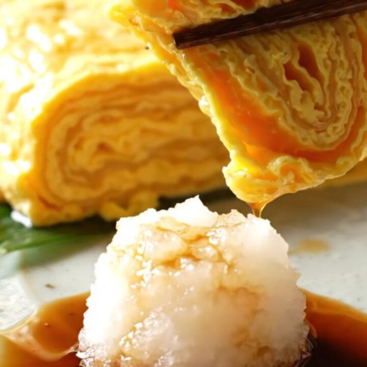 A close-up of a golden, multi-layered Japanese tamagoyaki omelette sliced into perfect rectangular pieces.