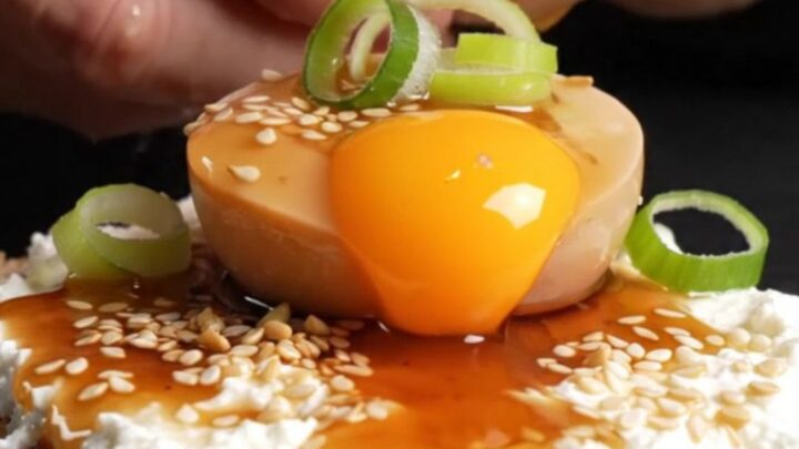 A close-up shot of a jammy soy-marinated egg sliced in half, revealing a translucent amber yolk on toasted sourdough bread.
