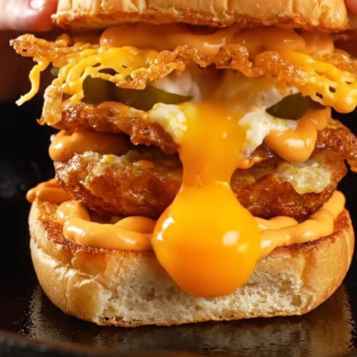 A crispy cheddar-crusted fried egg sitting on a toasted potato bun, showing a beautiful golden-brown lacy edge.