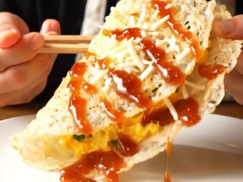 A close-up of a golden, blistered rice paper crepe filled with fluffy eggs and melted cheese.