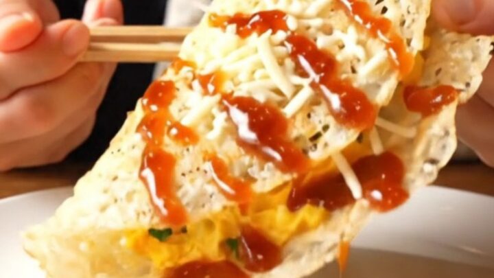 A close-up of a golden, blistered rice paper crepe filled with fluffy eggs and melted cheese.