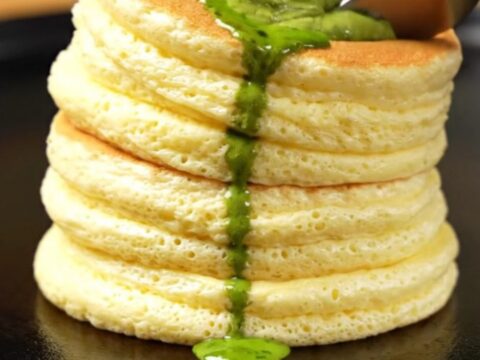 Two tall, jiggly Japanese cloud pancakes stacked on a plate with melting matcha butter.