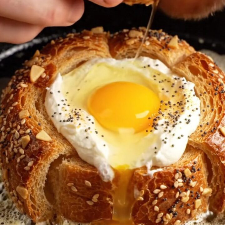 A close-up of a crispy golden brioche slice with a perfectly runny egg yolk in the center