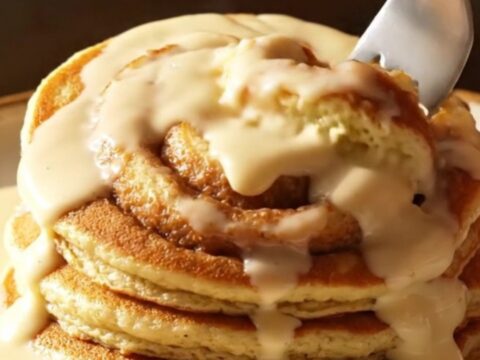 A stack of golden brown buttermilk pancakes with a beautiful dark cinnamon sugar swirl and drizzled with creamy white icing.