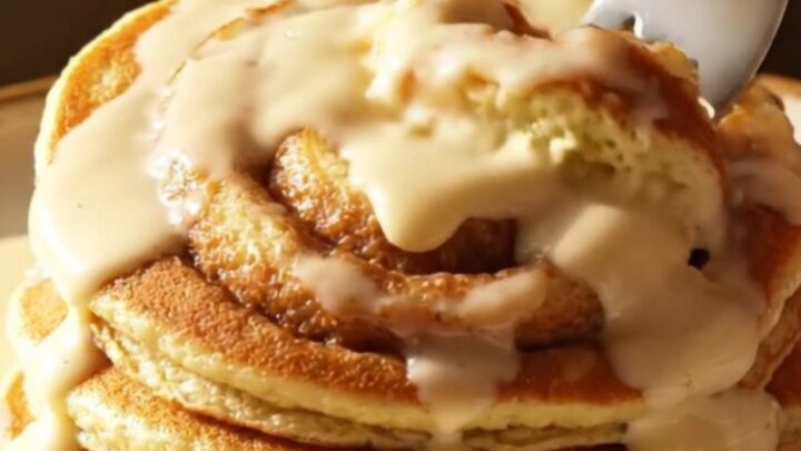 A stack of golden brown buttermilk pancakes with a beautiful dark cinnamon sugar swirl and drizzled with creamy white icing.