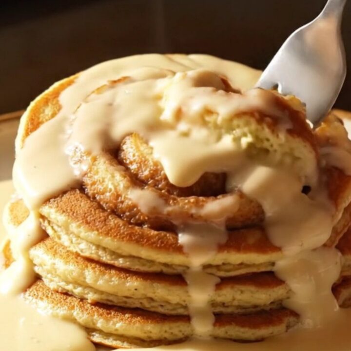 A stack of golden brown buttermilk pancakes with a beautiful dark cinnamon sugar swirl and drizzled with creamy white icing.