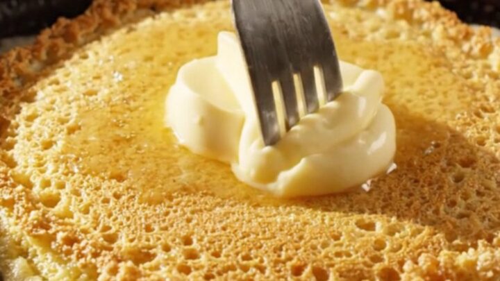 Crispy golden cornmeal pancakes stacked with a dollop of melting honey butter on top.