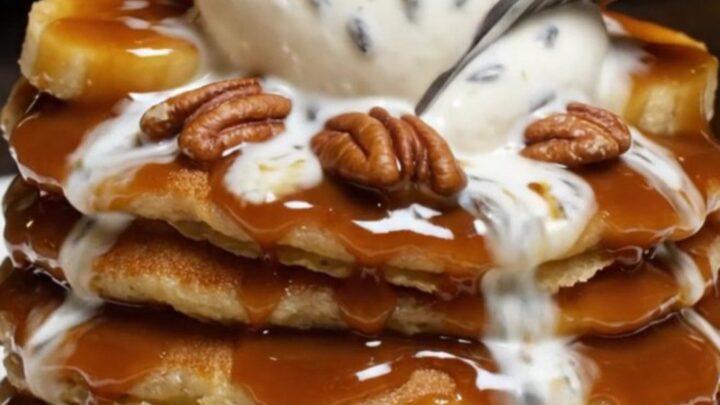 A stack of fluffy pancakes topped with caramelized bananas, toasted pecans, and a melting scoop of mascarpone.