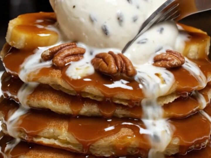 A stack of fluffy pancakes topped with caramelized bananas, toasted pecans, and a melting scoop of mascarpone.