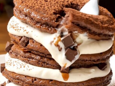 A stack of fluffy Tiramisu pancakes topped with whipped mascarpone and a dusting of cocoa powder.