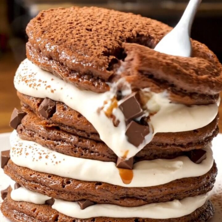 A stack of fluffy Tiramisu pancakes topped with whipped mascarpone and a dusting of cocoa powder.