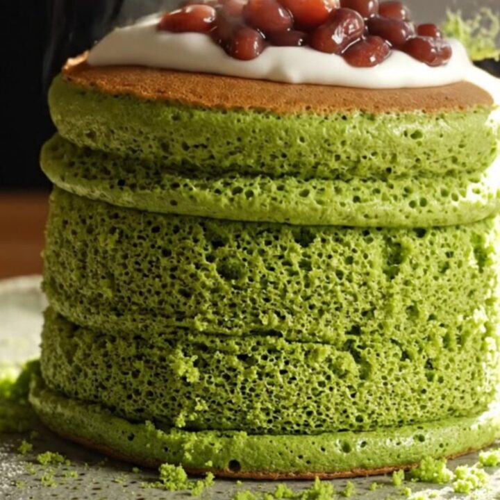 Two emerald matcha soufflé pancakes topped with sweet red beans and cream.