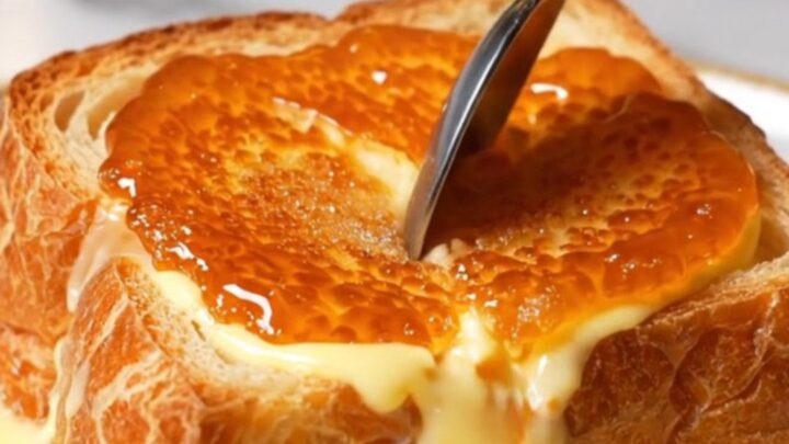 A close-up of a thick slice of golden-brown French toast topped with a perfectly caramelized, amber-colored sugar crust.