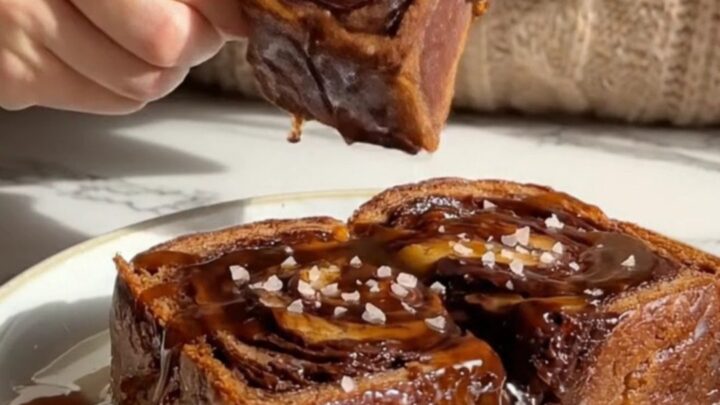 A slice of golden-brown chocolate babka French toast topped with glossy espresso syrup and sea salt.