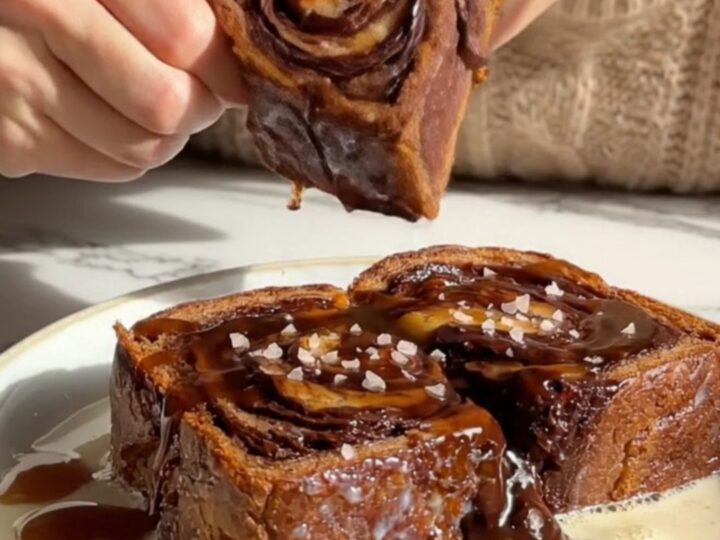 A slice of golden-brown chocolate babka French toast topped with glossy espresso syrup and sea salt.