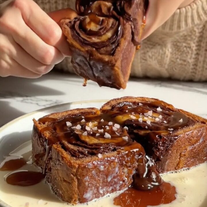 A slice of golden-brown chocolate babka French toast topped with glossy espresso syrup and sea salt.