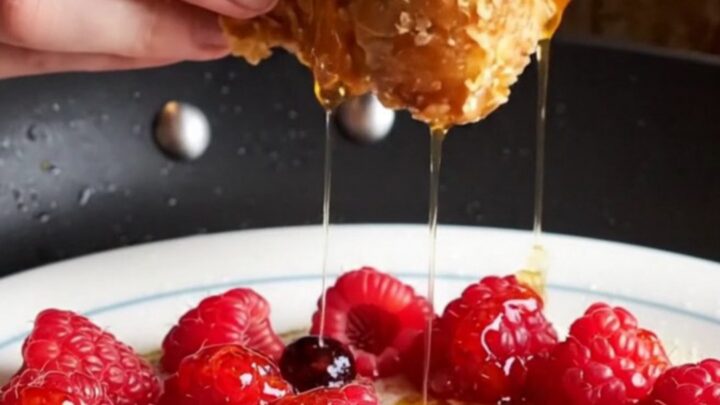A close-up of golden-brown cornflake-crusted French toast topped with fresh berries and maple syrup.
