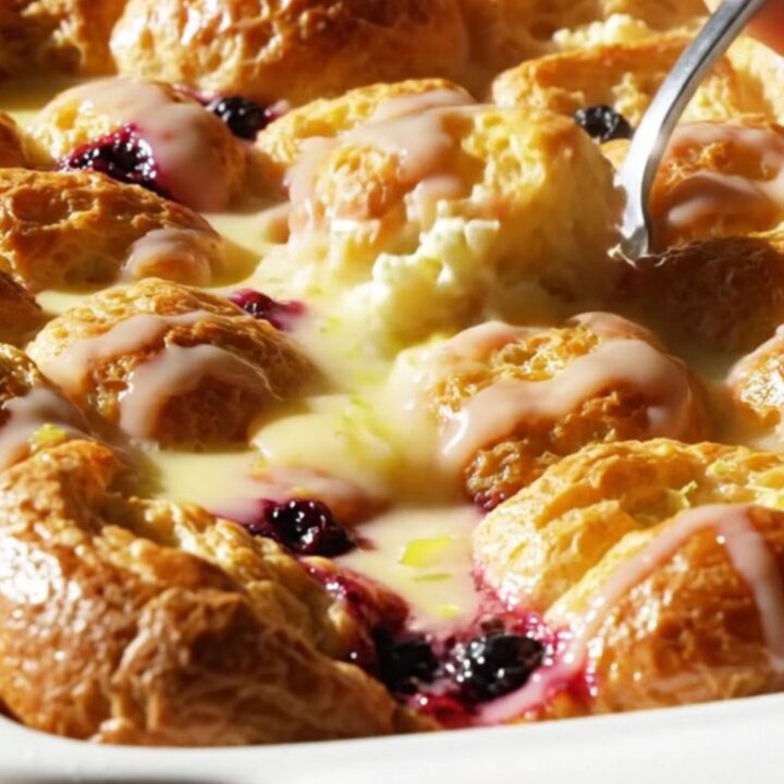 A golden-brown lemon blueberry French toast bake in a ceramic dish, topped with a bright lemon glaze.