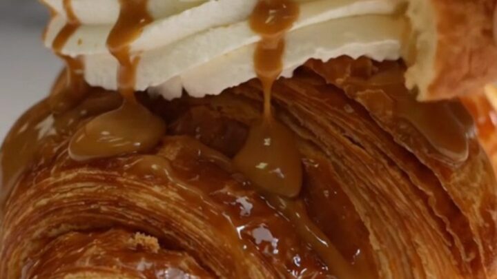 A golden-brown, caramelized croffle topped with whipped cream, cookie butter drizzle, and biscuit crumbs.