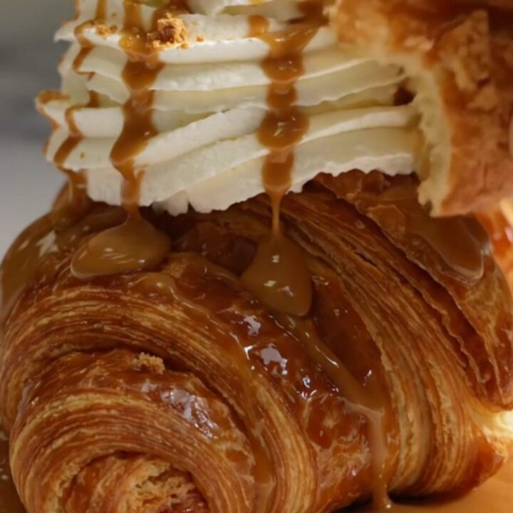 A golden-brown, caramelized croffle topped with whipped cream, cookie butter drizzle, and biscuit crumbs.
