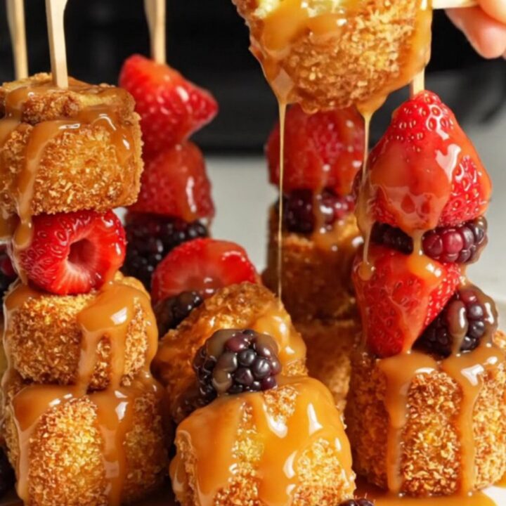A close-up shot of crispy air-fryer cinnamon roll French toast skewers drizzled with maple icing and garnished with fresh