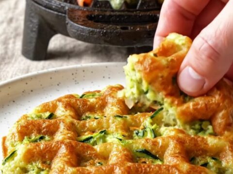 A crispy golden zucchini cheddar waffle topped with smoked salmon, dill crème fraîche, and bright orange salmon roe.