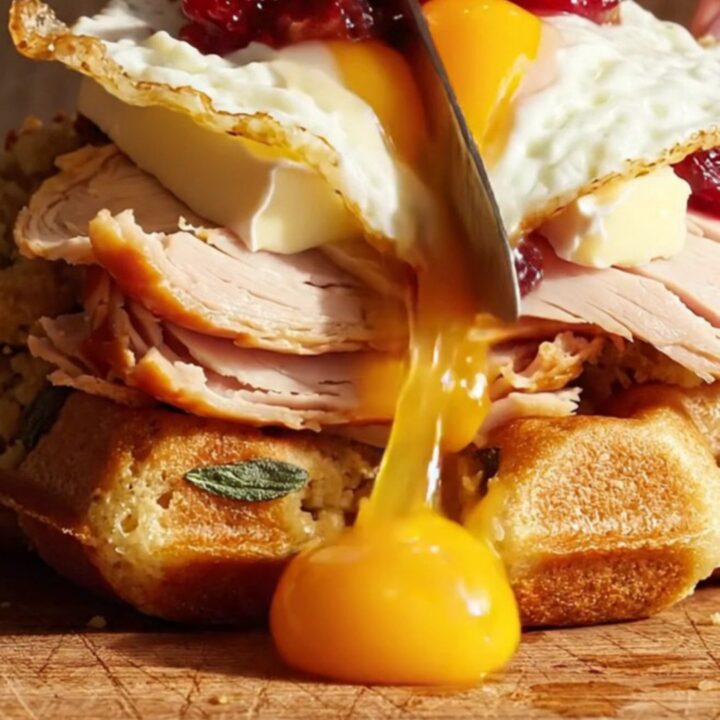 A crispy herb stuffing waffle sandwich filled with melted Brie, turkey, and cranberry, topped with a fried egg.