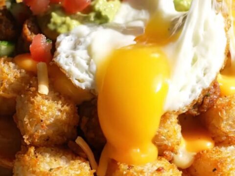A crispy, golden tater tot waffle topped with sizzling chorizo, melted cheese, and a sunny-side up egg.