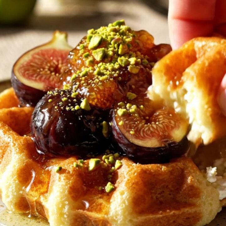 Close up of golden almond ricotta waffles topped with jammy black mission figs and honey.
