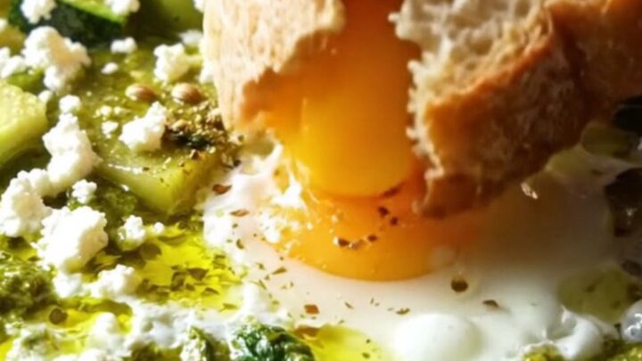 A cast iron skillet filled with green shakshuka, featuring eggs, spinach, and feta, shot in bright morning light.